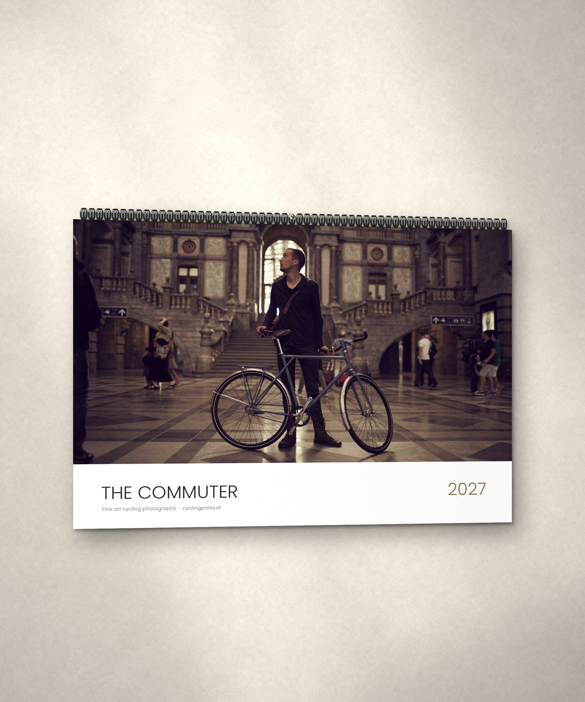 The Commuter 2027 cycling photography calendar hanging on a wall