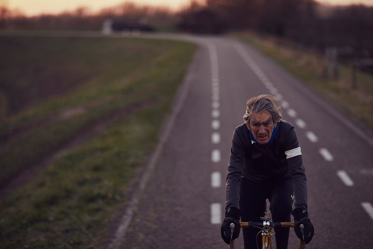 Nederlandse Wielerfotografie 'Between the Lines' - Albert, een 82-jarige wielrenner, op zijn op maat gebouwde stalen fiets langs de Waal- en Lekdijken, Nederland, fine art print door Cyclingprints.nl