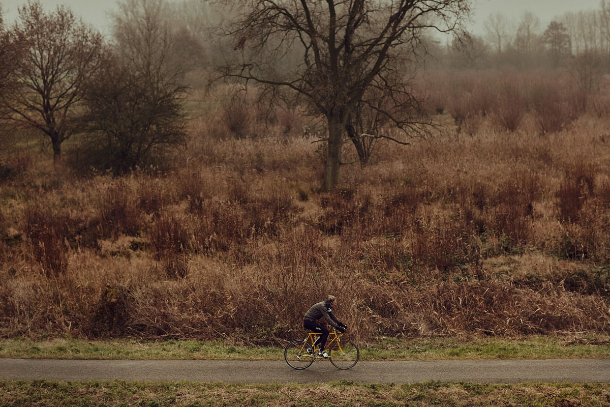 Nederlandse Wielerfotografie 'Cutting thru the Gloom' - Albert, een 82-jarige wielrenner, op zijn op maat gebouwde stalen fiets langs de Waal- en Lekdijken, Nederland, fine art print door Cyclingprints.nl