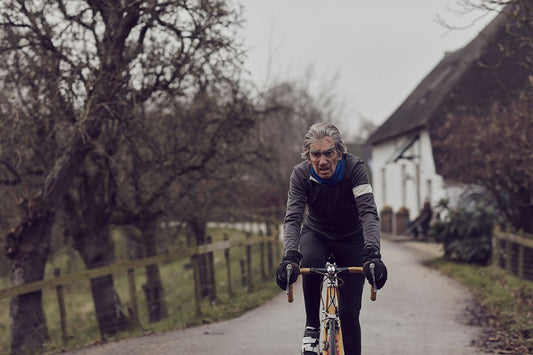 Nederlandse Wielerfotografie 'Leaden Skies' - Albert, een 82-jarige wielrenner, op zijn op maat gebouwde stalen fiets langs de Waal- en Lekdijken, Nederland, fine art print door Cyclingprints.nl